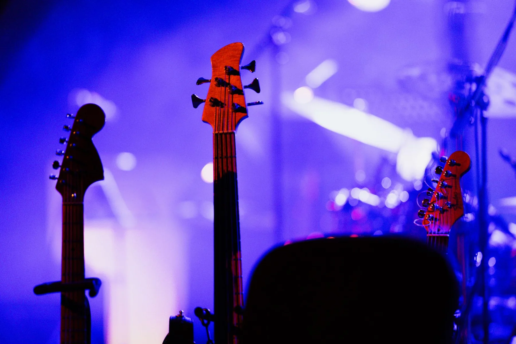 Electric guitars on stage under violet and magenta concert lighting